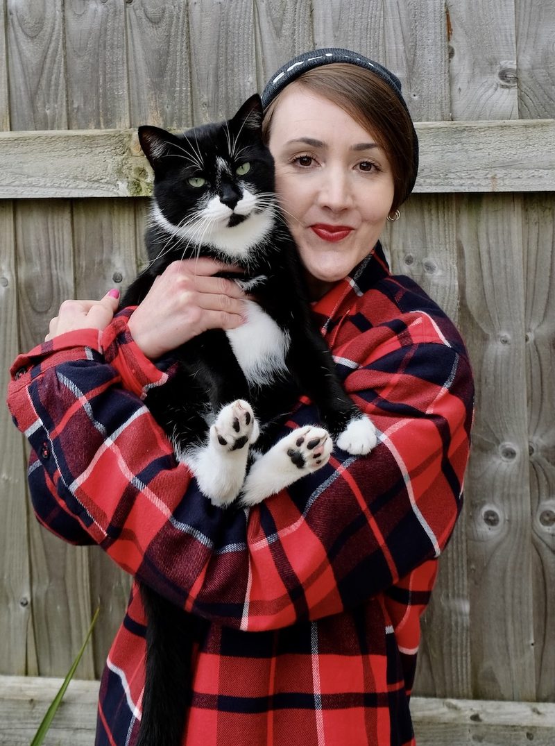 Leanne holding one of her cats, a black and white tuxedo cat